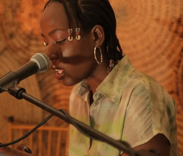 Une jeune chanteuse chante au micro, lumière orangée