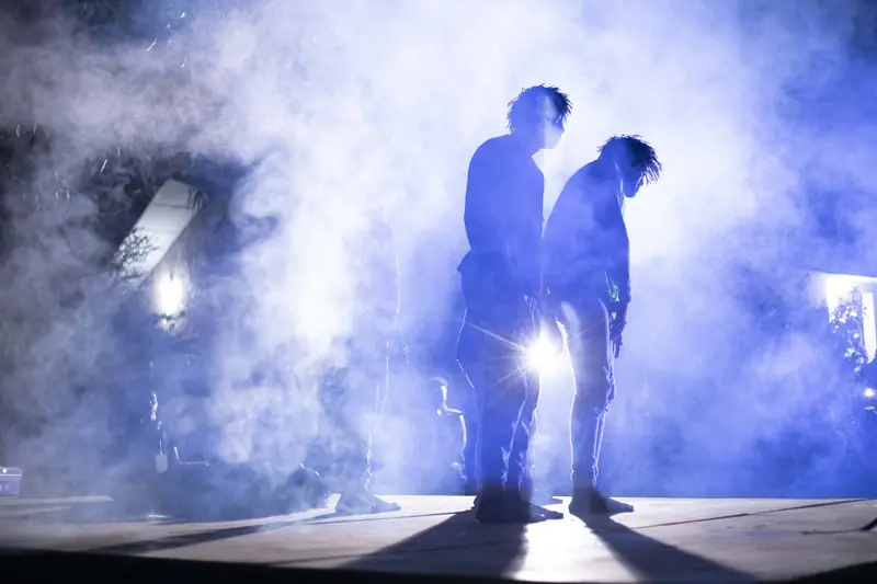 Des danseurs en silhouette dans la fumée, éclairés par les projecteurs