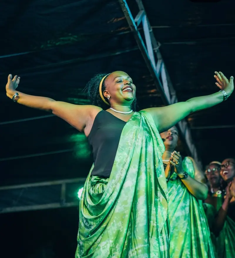 Une danseuse en tenue traditionnelle verte ouvre grand les bras