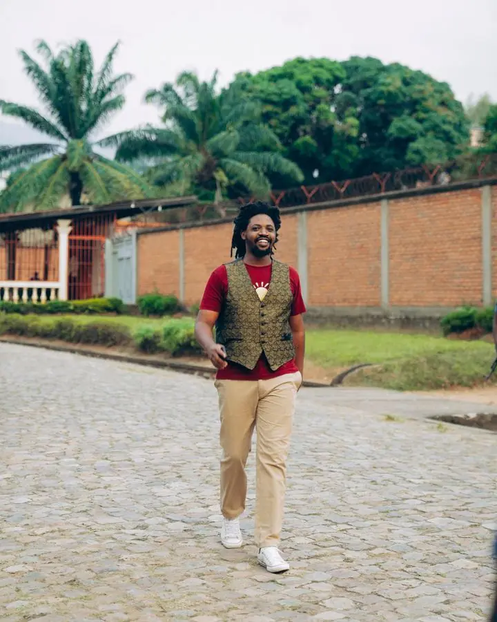 Rocky Mutamba marche en souriant sur une allée pavée